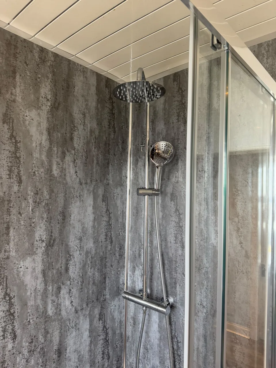 Chrome shower fittings against grey wall panels